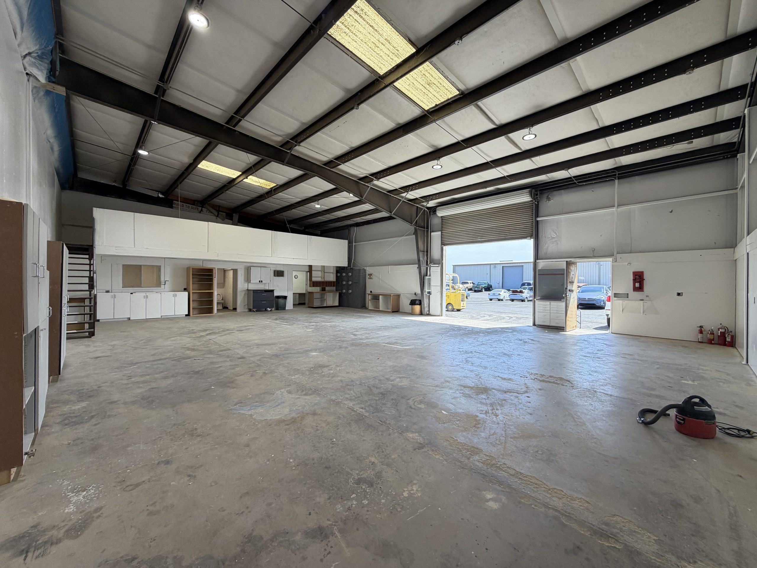 Open warehouse floor with roll-up door, mezzanine level, and built-in cabinetry — industrial flex space for lease at 511 Wilbur Ave, Antioch, CA